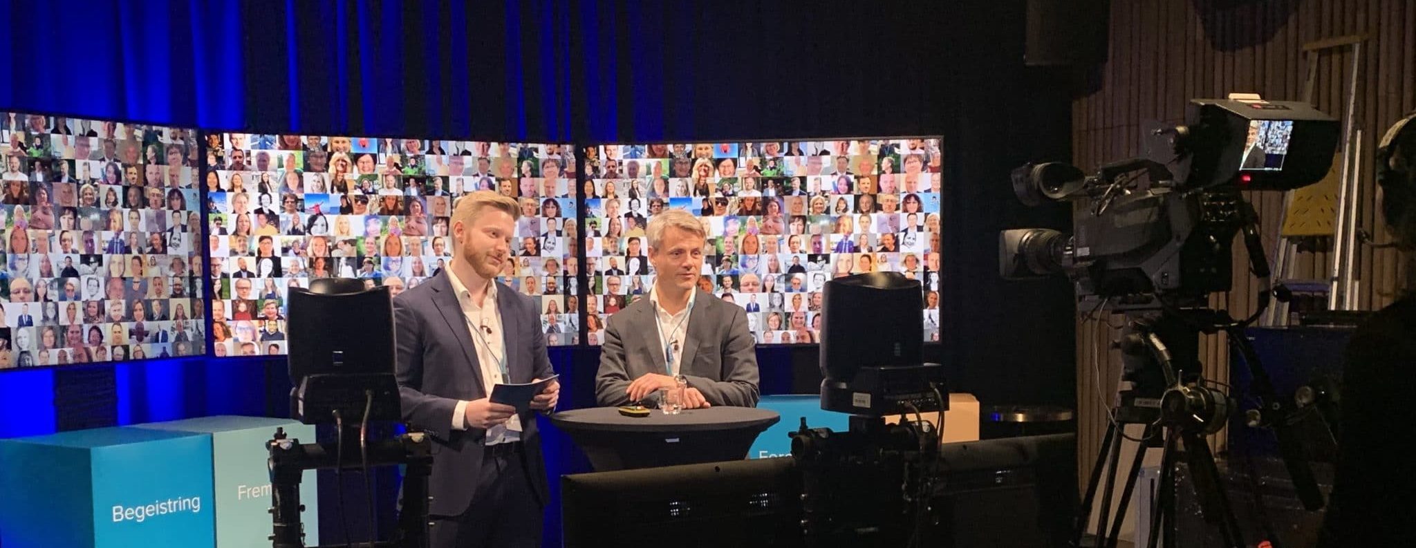 To menn stående i tv-studio foran skjermen